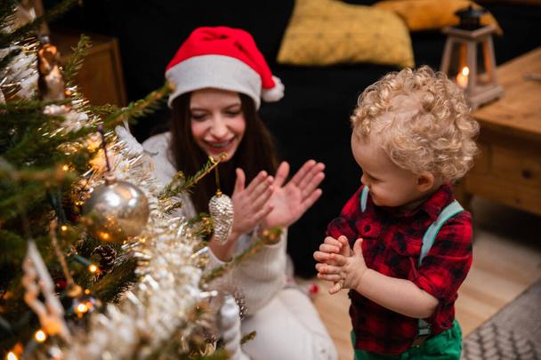 A teenage girl applauds her younger brother for a well-decorated Christmas tree. - Fotografie, Obrázek