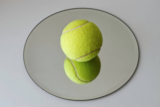 Tennis ball isolated on reflective surface - Photo, Image