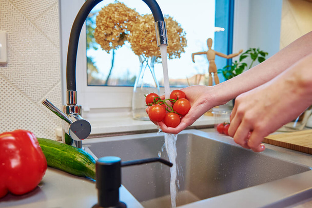 Женщина моет помидоры у раковины на кухне - Фото, изображение