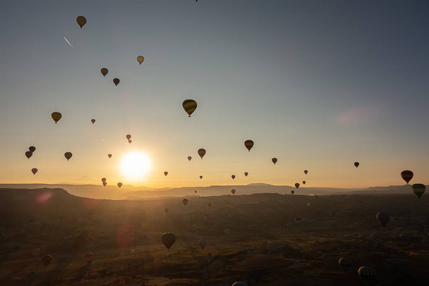 Hete lucht ballonnen in de lucht tijdens de zonsopgang. Vliegen over de vallei in Cappadocië, Anatolië, Turkije. Vulkanische bergen in Goreme nationaal park. - Foto, afbeelding