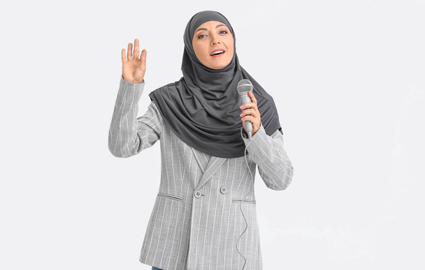 Muslim music teacher with microphone on light background - Foto, afbeelding