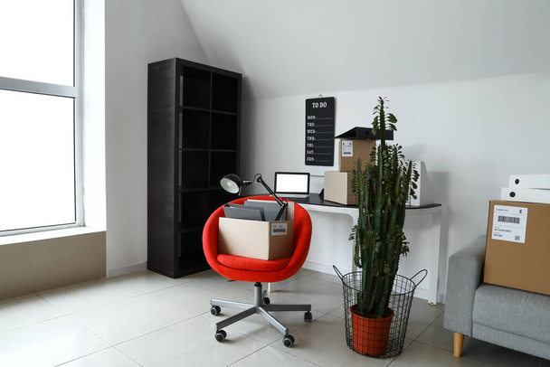 Cardboard boxes with belongings and furniture in interior of office on moving day - Photo, Image