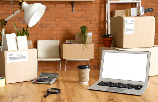 Caixas de papelão com pertences e laptop na mesa no escritório no dia em movimento - Foto, Imagem