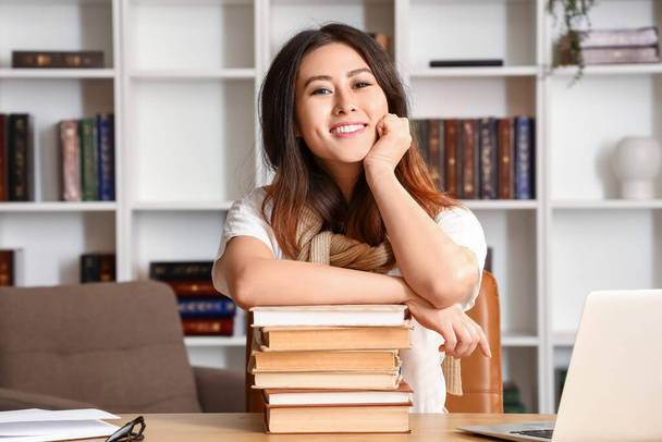 Молодой преподаватель из Азии с книгами, сидящими дома - Фото, изображение