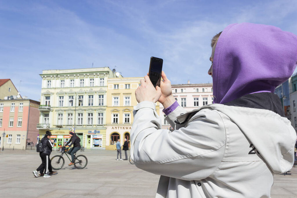 Young man, tourist holding him smart phone and taking photo in the center of european city. - Photo, Image