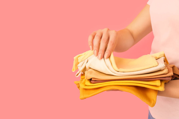 Woman with stack of baby clothes on pink background, closeup - Photo, Image