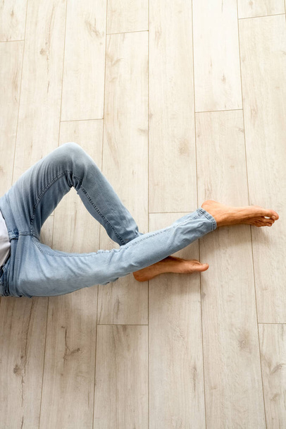 Junger barfüßiger Mann sitzt auf Holzboden - Foto, Bild