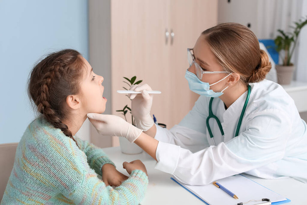 Médico examinando la garganta de una niña en la clínica - Foto, imagen