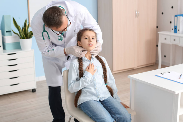 Доктор вивчає шию маленької дівчинки в клініці
 - Фото, зображення