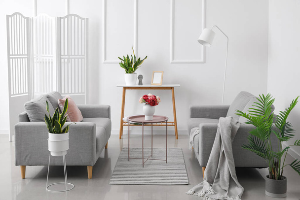 Сучасний інтер'єр вітальні зі зручними диванами і стильними столиками біля білої стіни
 - Фото, зображення