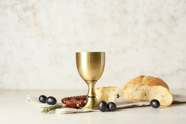 Cup of wine with bread and rosary on light background - Photo, Image