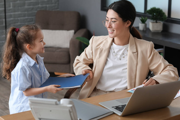 Working young mother with her little daughter in office - Foto, Bild