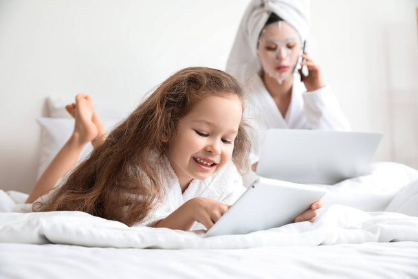 Little daughter with her working mother in bedroom - Photo, image