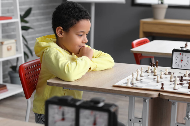 Kleine Afro-Amerikaanse jongen schaken tijdens toernooi in club - Foto, afbeelding