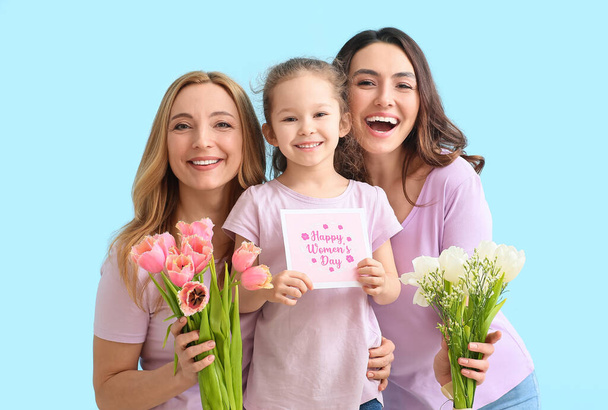 Young woman, her little daughter and mother with flowers and greeting card for International Women's Day on color background - Foto, Imagen