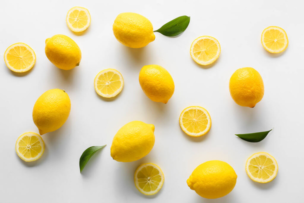 Many ripe lemons and slices on white background, top view - Photo, image