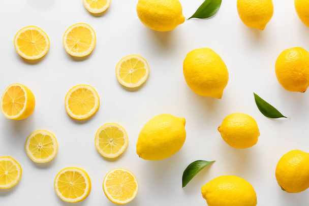 Many ripe lemons and slices on white background, top view - Foto, afbeelding