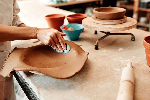 I have to smooth it out first. Cropped shot of an unrecognizable artisan working in a pottery workshop. - Foto, imagen