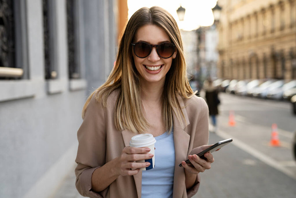 Πορτρέτο μιας επιτυχημένης νεαρής γυναίκας που χρησιμοποιεί ψηφιακό tablet κατά τη διάρκεια γρήγορου διαλείμματος σε αστικό περιβάλλον - Φωτογραφία, εικόνα