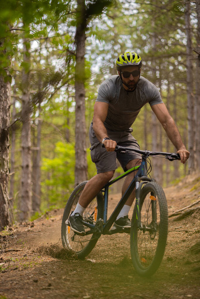 Knap en fit man drijft met zijn fiets in het bos - Foto, afbeelding