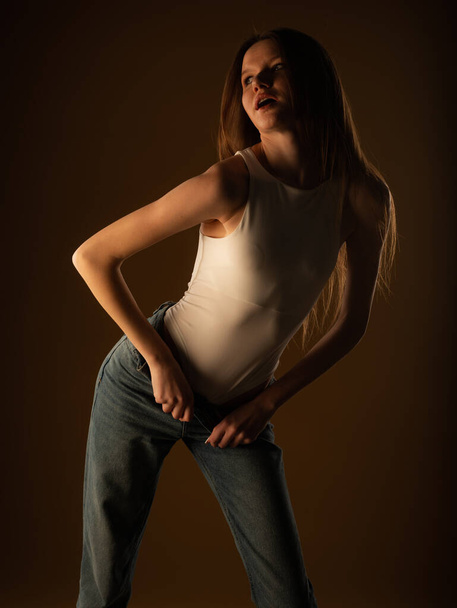 Attractive and beautiful young girl is holding her posture and posing in studio on yellow background - Fotografie, Obrázek