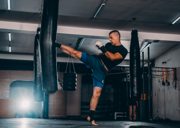 Action of a boxing martial arts fighter training on a punching bag in the gym - Fotó, kép