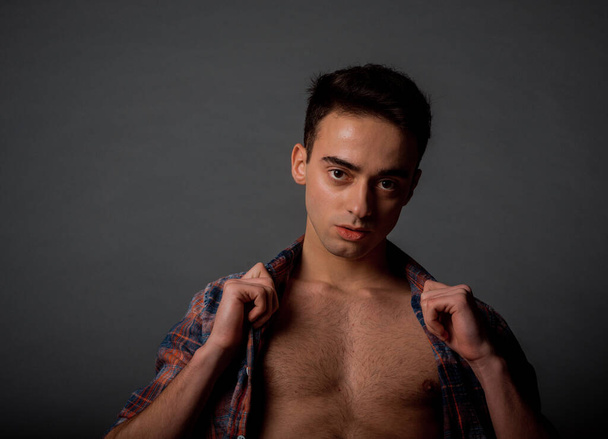 Portret van een aantrekkelijke jonge man poseren in moderne unbuttoned geruite shirt - Foto, afbeelding