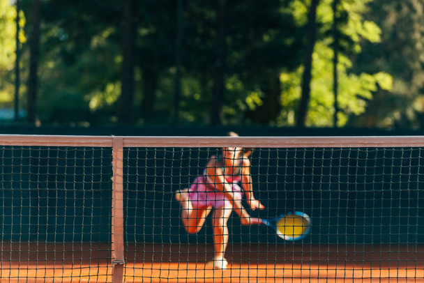Hezká žena tenista pozorovaný přes síť. - Fotografie, Obrázek