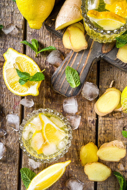 Homemade ginger lemonade cocktail. Cold summer ginger lemon ale. Sweet and sour iced refreshing beverage with lemon slice garnish,  Detox and weight loss drink concept. Wooden rustic background copy space - Photo, Image