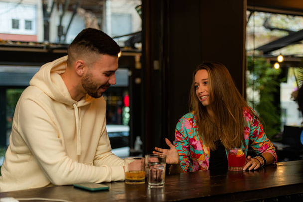 Aantrekkelijke en knappe jonge man flirt met het meisje terwijl praten en drinken - Foto, afbeelding