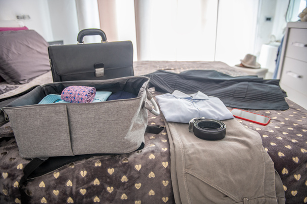 ビジネス旅行のための梱包スーツケース。ベッドの上の服やブリーフケース - 写真・画像
