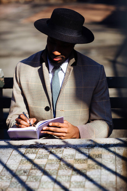 portrait of a young African man reading a book in a park - Photo, image