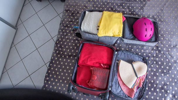 Faça as malas de férias na cama com roupas e chapéus. Embalagem para uma viagem - Foto, Imagem