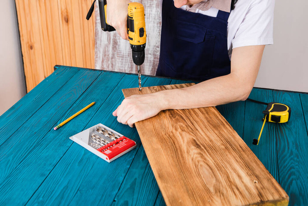 Handyman in blue uniform works with electricity automatic screwdriver. - Foto, immagini