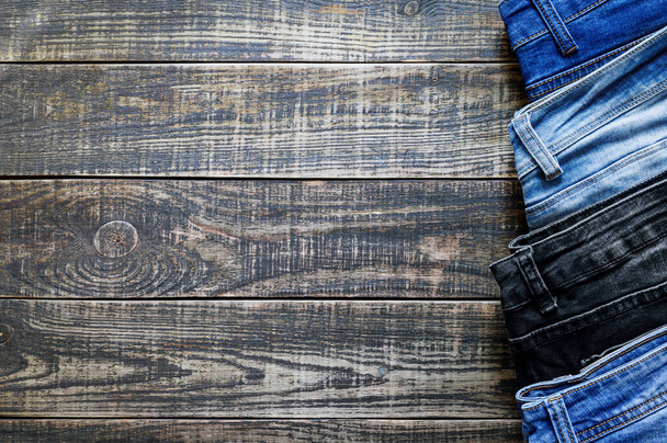 Jeans trousers on a rustic wooden background with copy space. Variety of comfortable casual trousers, top view. - Photo, Image