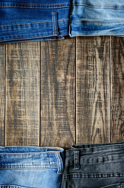 Textile background theme with different jeans on an old wooden table with copy space in the middle. Vertical view. - Photo, Image