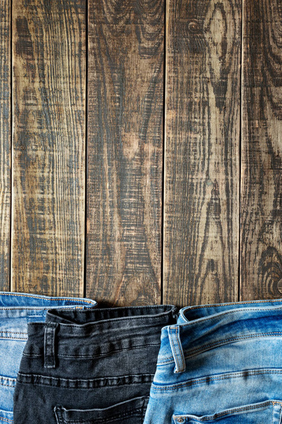 Textile background theme with different cotton jeans on an rustic wood with copy space. Vertical view. - Photo, Image