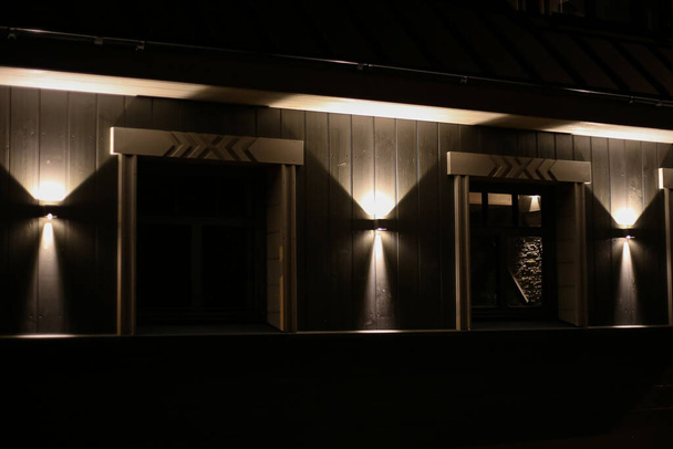 Сучасний архітектурний будинок з світлодіодним освітленням на фасаді. Фото зроблене в маленькому морському міському вечорі
. - Фото, зображення