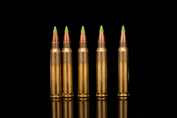 Un gruppo di 5.56 calibar, proiettili a punta verde ordinati nella linea su sfondo nero - Foto, immagini