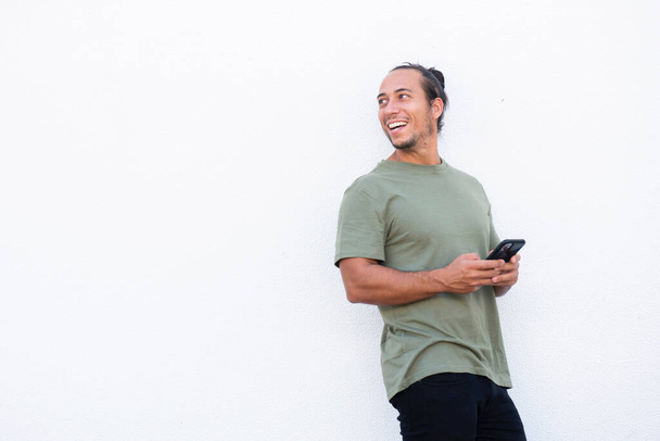 Homem feliz olhando para longe ao usar o telefone celular sobre fundo branco - Foto, Imagem