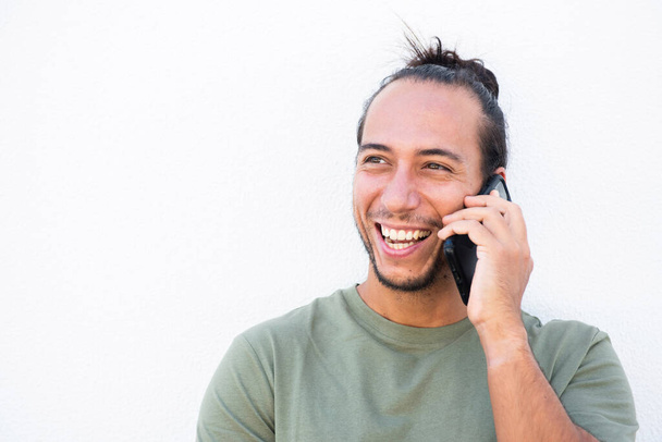 Hombre feliz con moño de pelo arrancado hablando en el teléfono móvil sobre fondo blanco - Foto, imagen