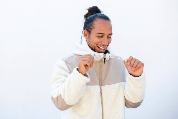 Man with pulled back hair bun in winter jacket having fun over white background - Photo, Image