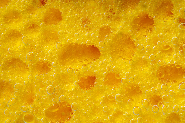 Texture of a sponge in water, close-up macro. The concept of washing dishes or cleaning cars. Abstract Yellow Wallpaper - Фото, изображение