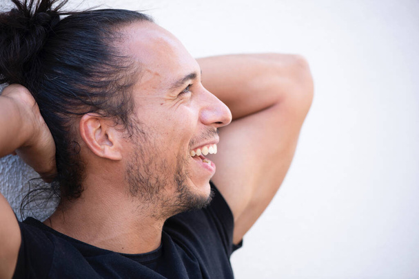 Χαρούμενος άνθρωπος με τραβηγμένα μαλλιά κουλούρι και τα χέρια πίσω από το κεφάλι πάνω από λευκό φόντο - Φωτογραφία, εικόνα