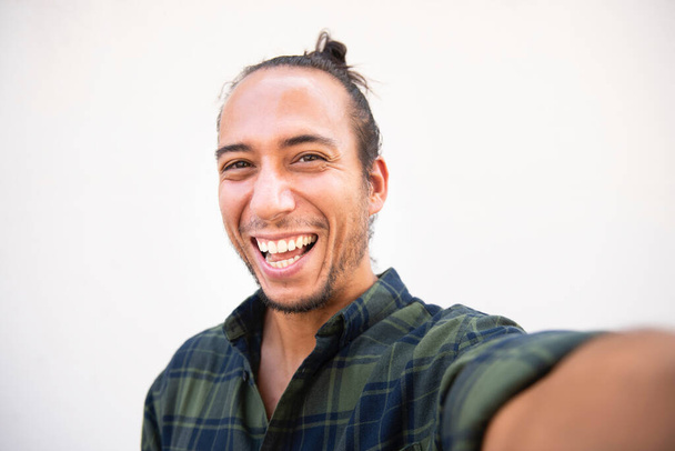 Porträt eines fröhlichen Mannes, der ein Selfie vor weißem Hintergrund macht - Foto, Bild