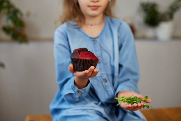 Menina comparando alimentos, escolhendo bolo doce contra microverde Hábito insalubre, conceito de desnutrição - Foto, Imagem