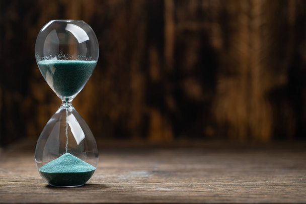 Selective focus of hourglass with green sand on wooden background - Φωτογραφία, εικόνα