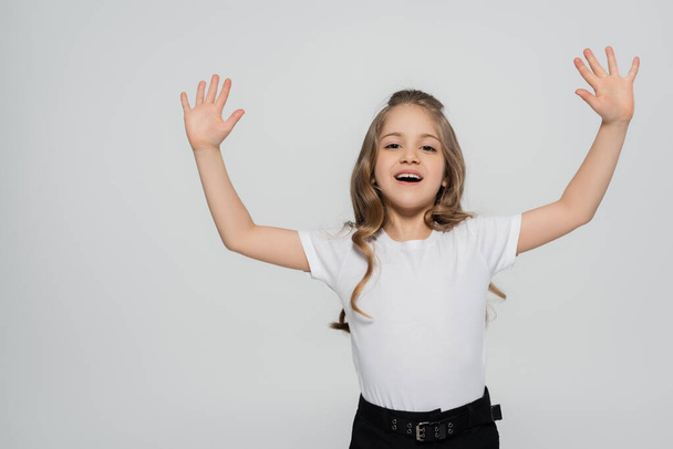 excited girl in white t-shirt waving hands while looking at camera isolated on grey - Foto, Imagem
