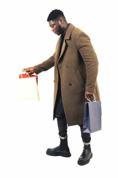 black guy holding a lot of bags white background - full shot - Foto, afbeelding