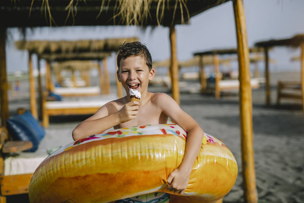 Niño en la playa comiendo helado en un día de verano y divirtiéndose. - Foto, Imagen
